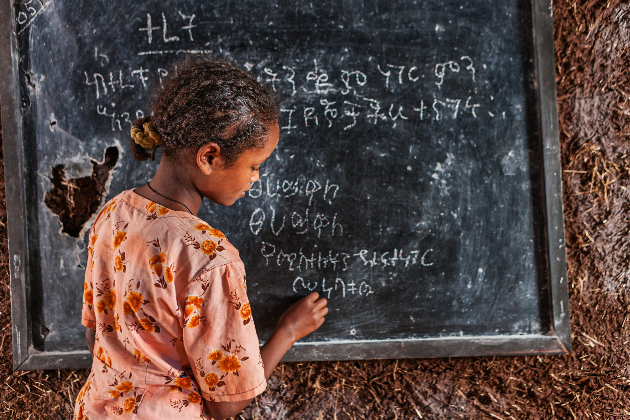 African little girl during her Amharic class in very remote school. The bricks that make up the walls of the school are made of clay and straw. There is no light and electricity inside the classroom