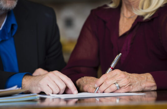 A senior citizen signing a document.